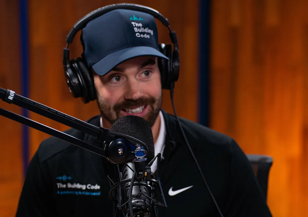 Construction industry podcast recording setup with microphone, headphones, and branded apparel in a studio.